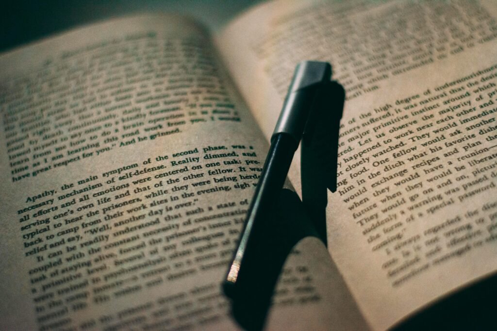 Close-up of a ballpoint pen resting between the pages of an open book, perfect for education or reading themes.